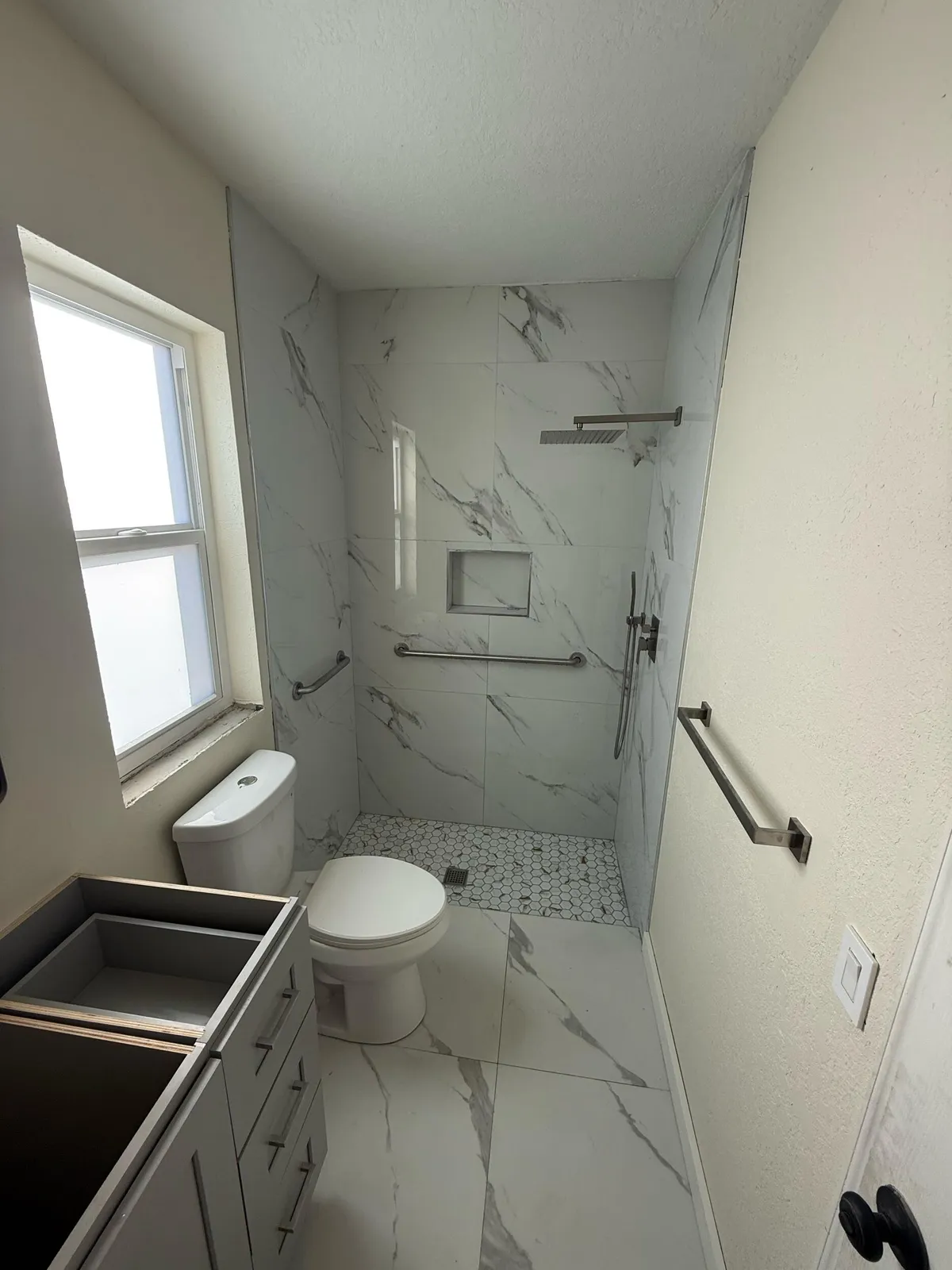 Remodeled bathroom with a marble-look walk-in shower in a Palm Beach County home, by MGS