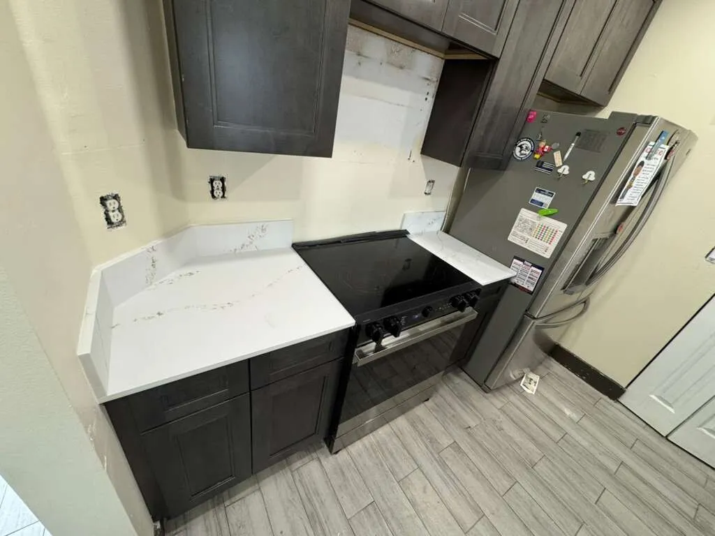 Remodeled kitchen with quartz counters, dark cabinets and plank flooring in a Miami-Dade home, by MGS